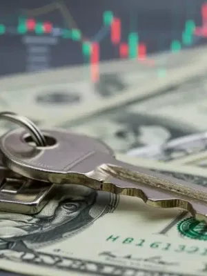 House key on dollar bills with rising financial chart, symbolizing mortgage refinancing outlook.